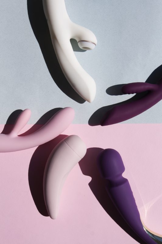 Collection of different types of sex toys on a blue and pink background.